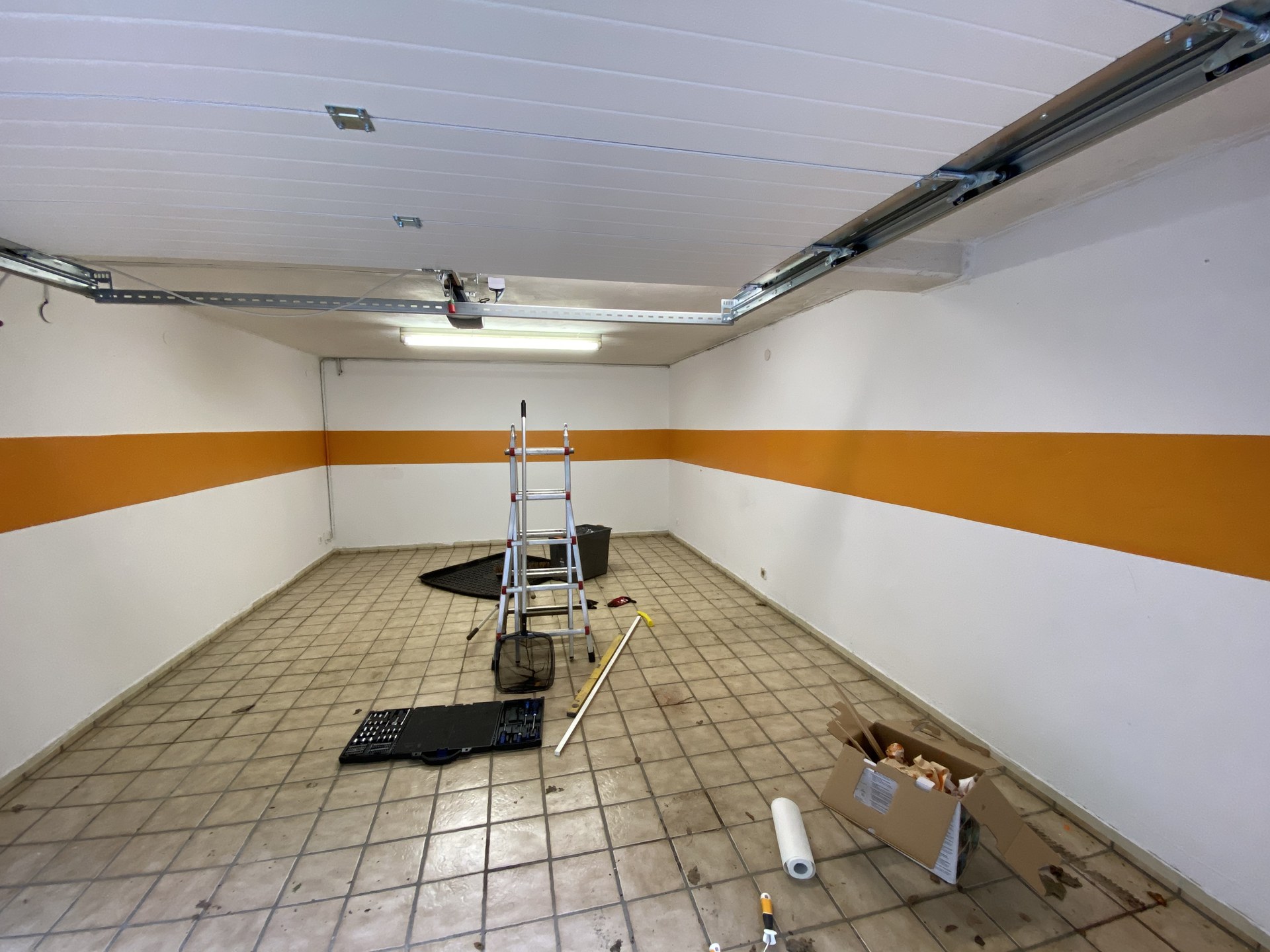 Frisch gestrichener orangefarbener Wandstreifen in der noch leeren Garage