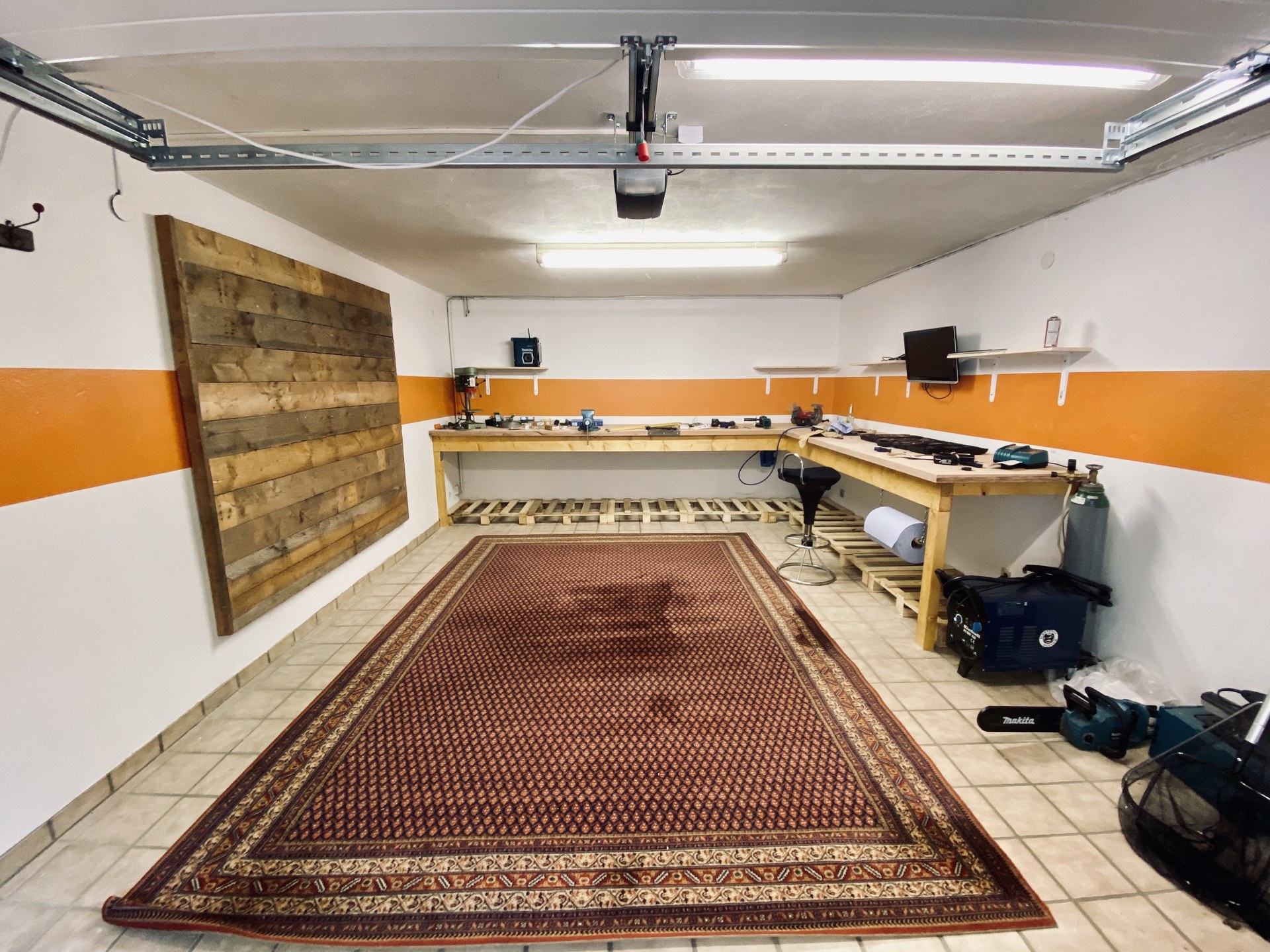 Garage mit Eckwerkbank, Werkzeug und großem Teppich während der Einrichtung