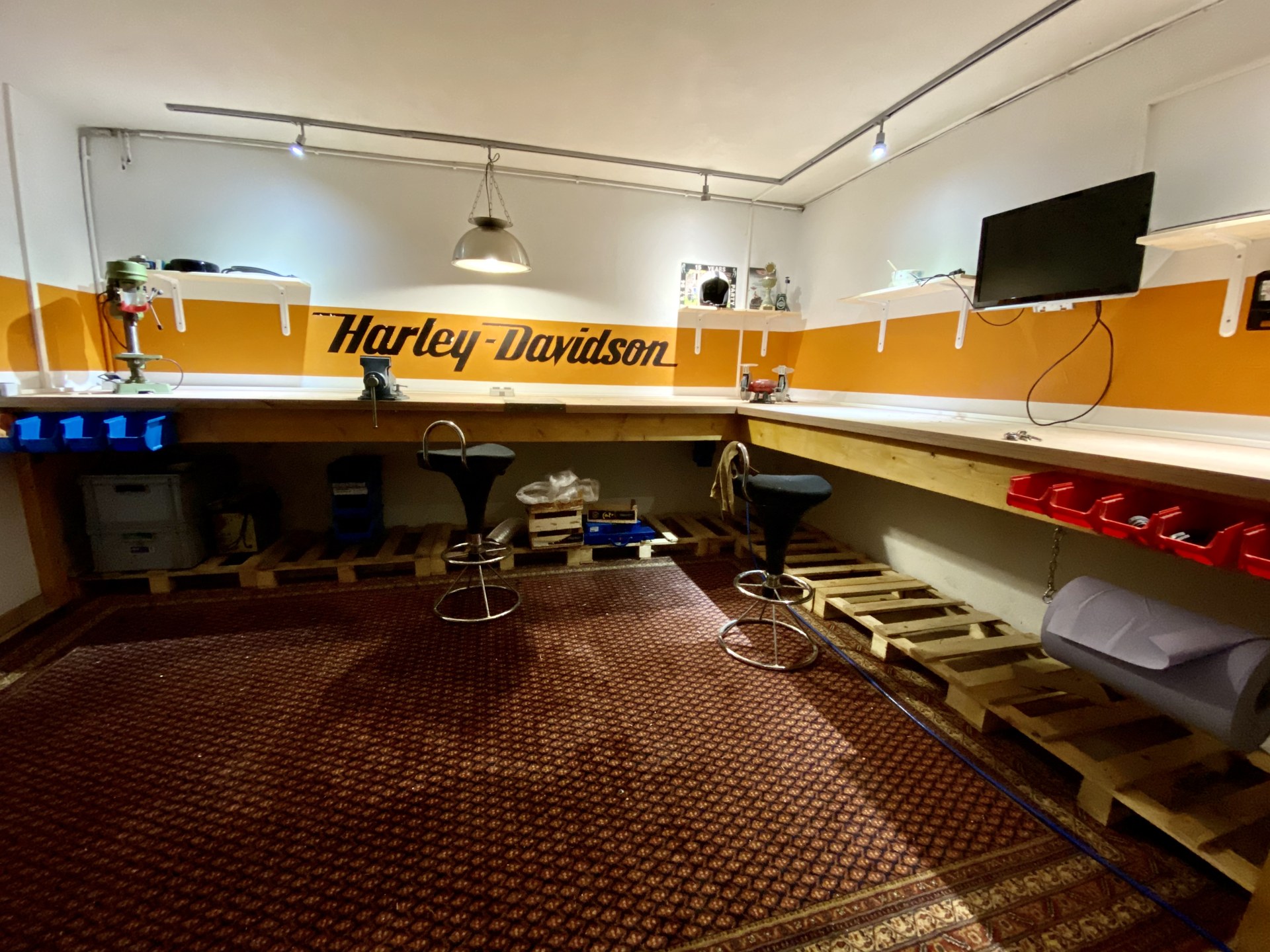 Eingerichtete Werkstatt mit Harley-Davidson-Schriftzug, Werkbank und Barhockern