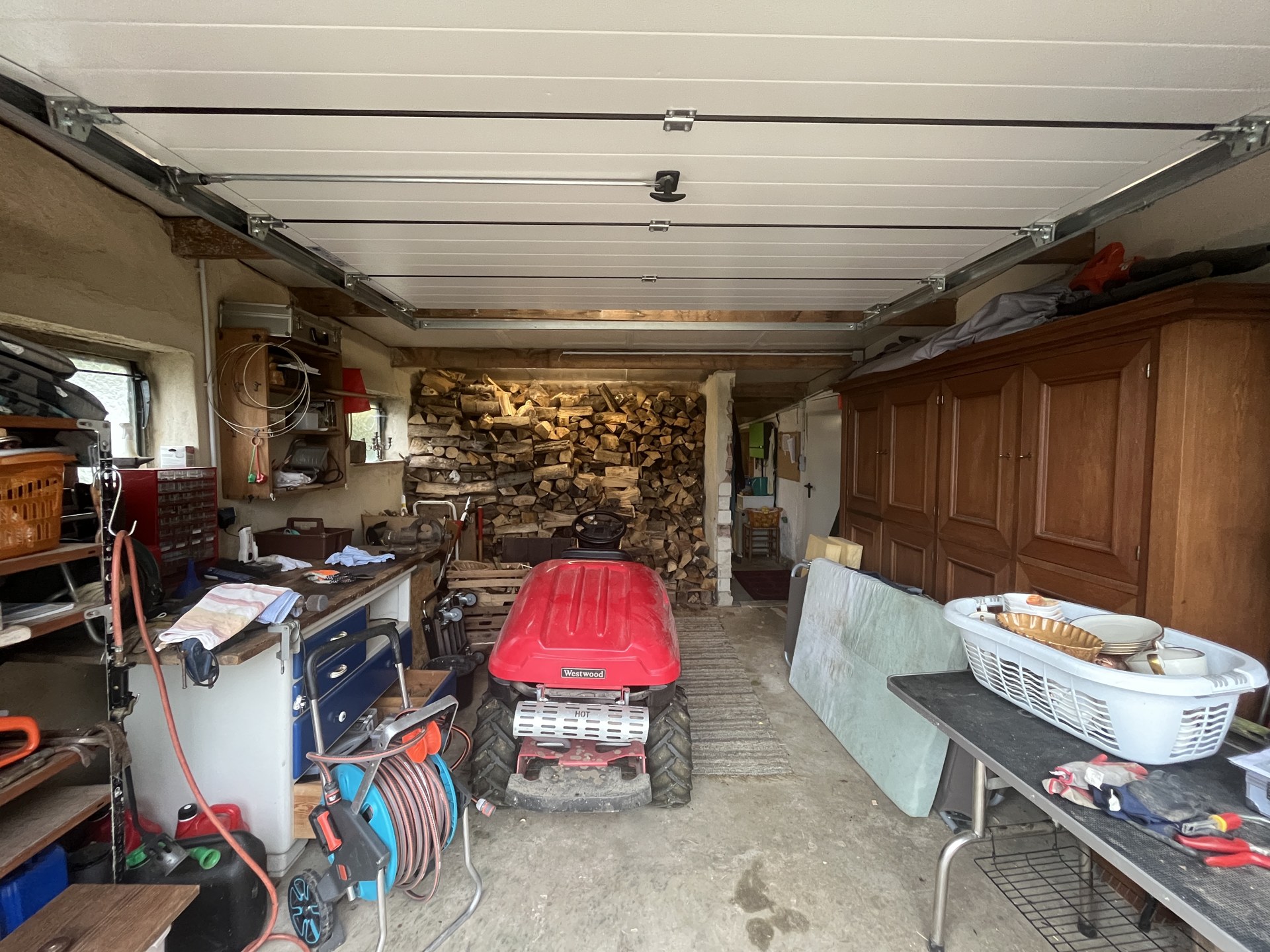 Ursprüngliche Garage in Hüllhorst mit Aufsitzmäher, Brennholz und alten Schränken